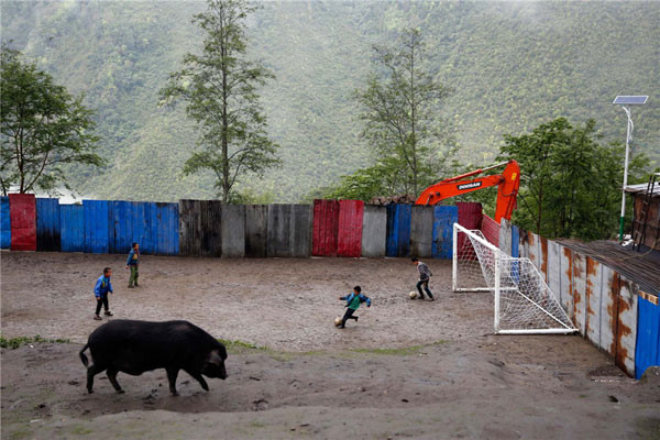 Children play football at school while a hog looks for food at Bangxin Village School in Medog county,Tibet. Although the playground is surrounded by a sheet-metal fence, it is not unusual for children to kick their football off the steep cliff