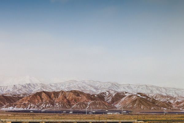 Landscape with snowy undulating mountains levels out after surmounting Tanggula Pass